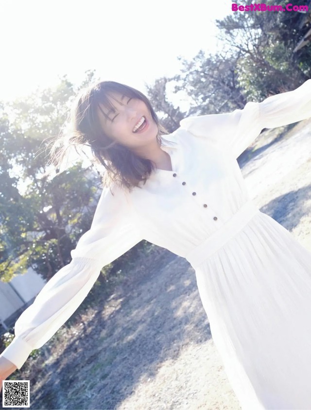 A woman in a white dress standing in a field.