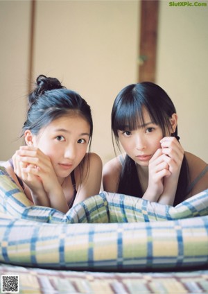 Two young women sitting on the floor in front of a window.