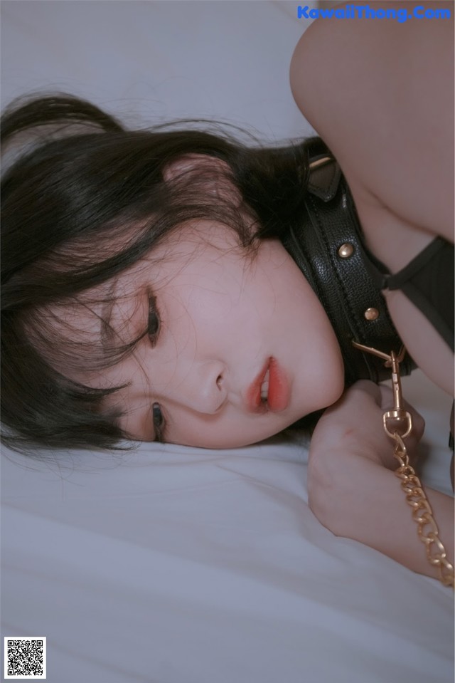 A woman laying on a bed with a chain around her neck.