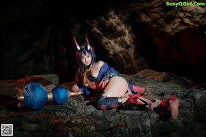 A woman in a blue and red outfit sitting on a rock.