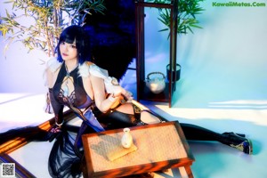 A woman in a blue and black outfit sitting on a chair.
