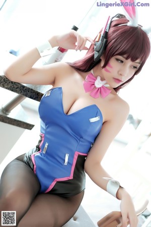 A woman in a blue dress with a pink bow on her neck.
