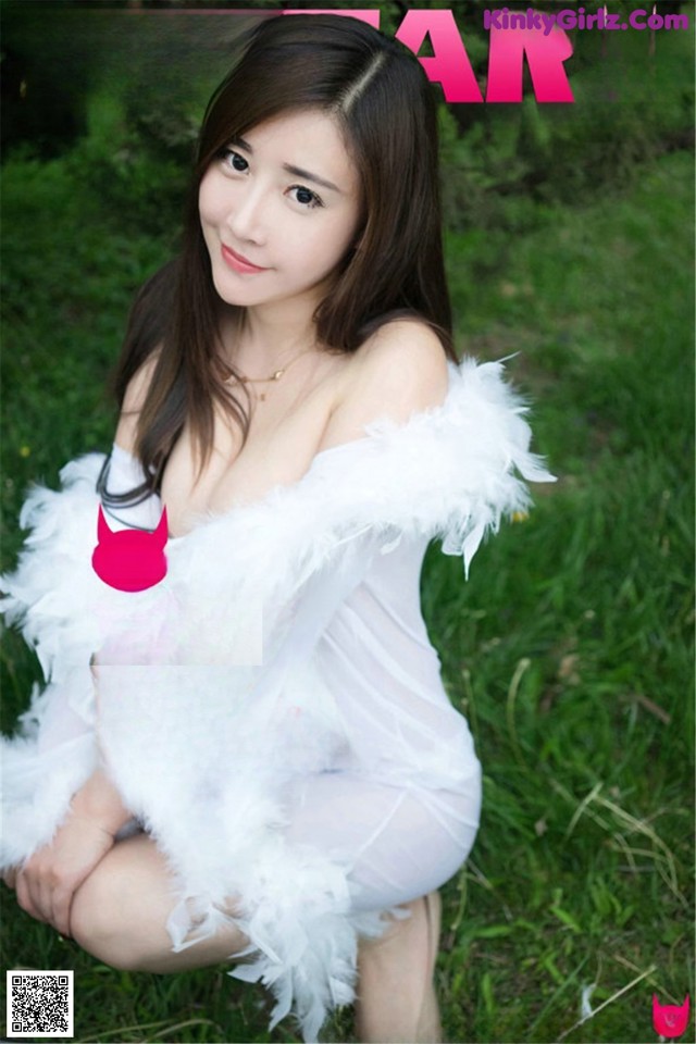 A woman in a white dress sitting on the grass.