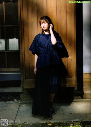 A woman standing in front of a building in a field.