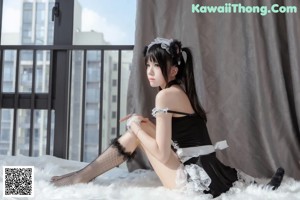 A woman in a maid outfit posing on a bed.
