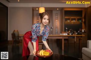 A woman in a red dress holding a bowl of fruit.