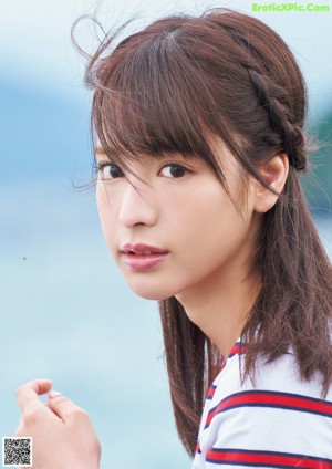 A woman standing next to a wooden fence by the water.