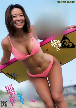 A woman in a pink bikini sitting on the beach.