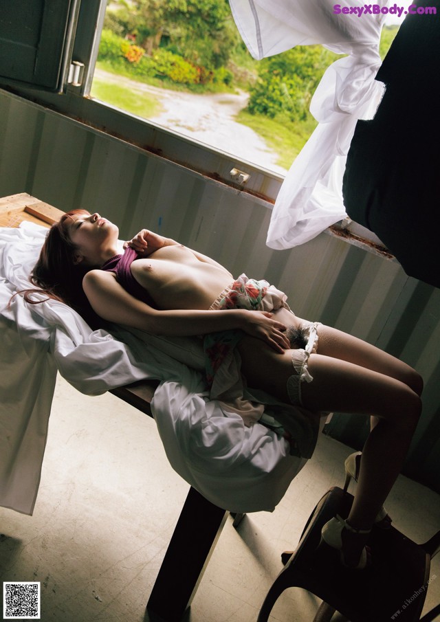 A woman laying on top of a bed next to a window.