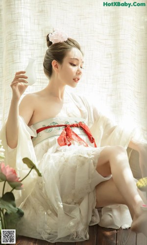 A woman in a pink lingerie sitting on a bed.