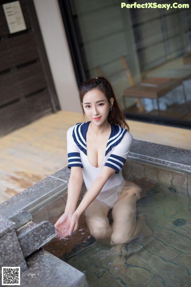 A woman in a white and blue sailor outfit sitting in a pool.