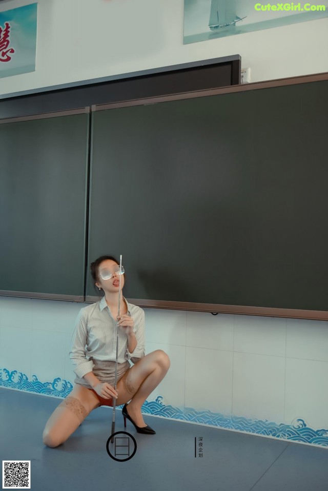 A woman sitting on the floor in front of a blackboard.