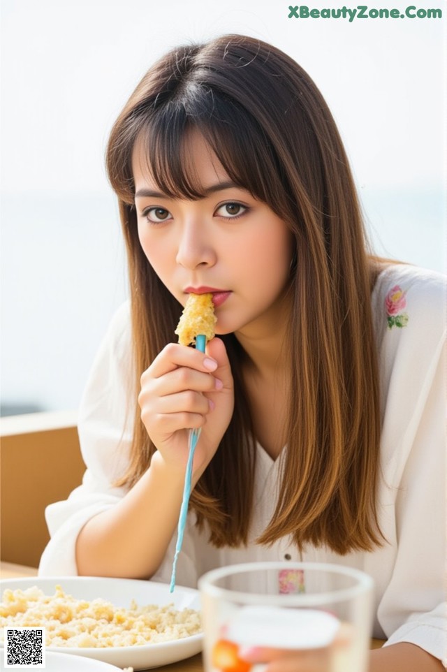 A woman sitting at a table eating a piece of food.
