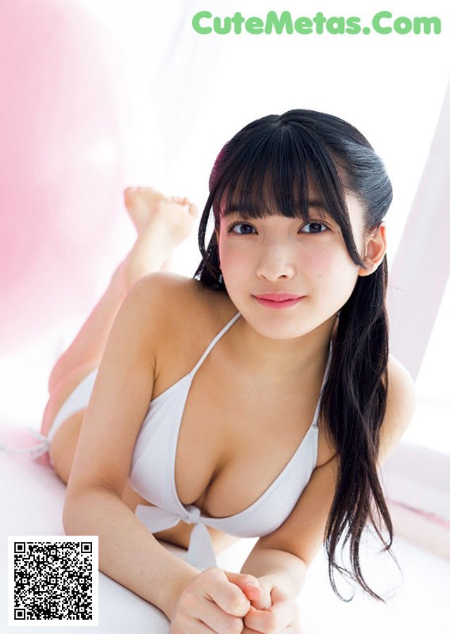A woman in a white bikini laying on a bed.