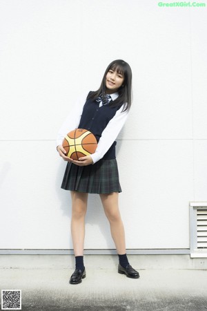 A young woman holding a basketball in her hand.