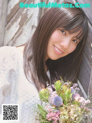 A woman with long black hair and bangs smiles at the camera.