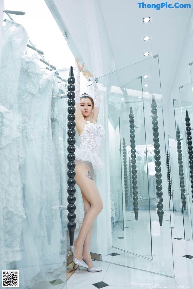 A woman in a white lingerie standing in front of a mirror.