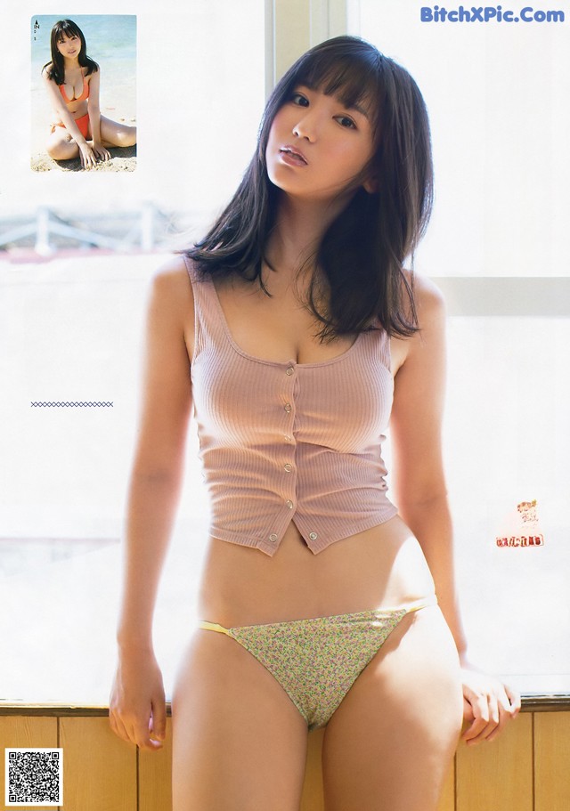 A woman in a bikini posing in front of a window.