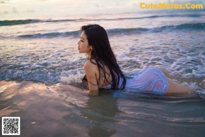 A woman in a purple lingerie sitting in the water.