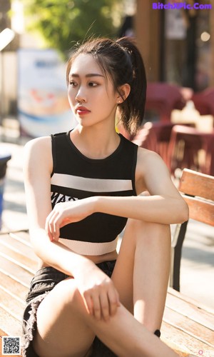 A woman sitting on a bench wearing a blue dress.