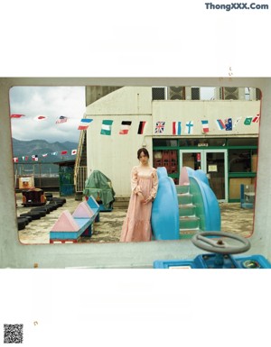 A woman in a pink dress standing in front of a building.