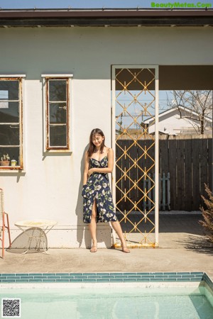 A woman leaning against a pole in front of a plant.