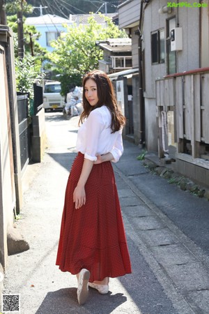 A woman in a red dress is sitting on a bench.