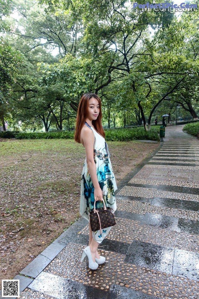 A woman in a blue and white dress standing on a sidewalk.