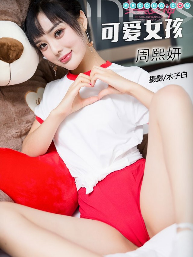 A woman in a white shirt and red shorts laying on a bed.