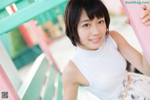 A woman in a white tank top and white skirt bending over.