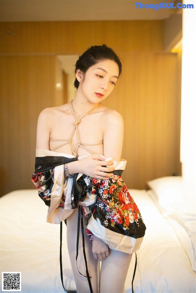 A woman in a kimono is posing on a bed.