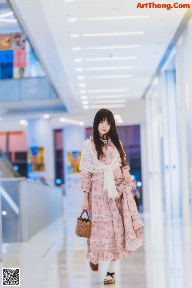 A woman in a pink dress is walking down a hallway.