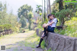 A woman in a school uniform sitting on a bench.