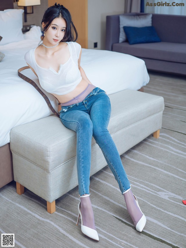 A woman sitting on a bed in a hotel room.