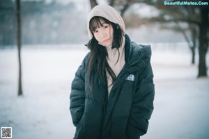 A woman wearing a face mask standing in the snow.