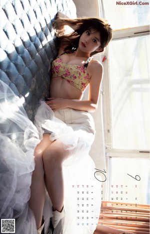 A woman in a floral dress laying on a bed.