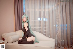 A woman with long green hair sitting on a couch.