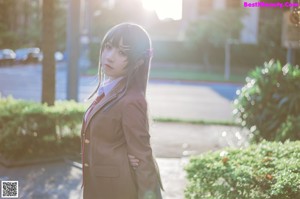 A woman in a school uniform holding a cell phone.