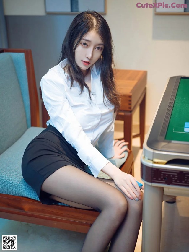 A woman sitting on a couch next to a printer.