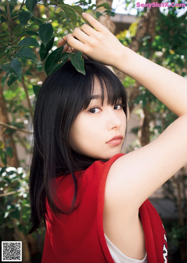 A woman in a red shirt is posing for a picture.
