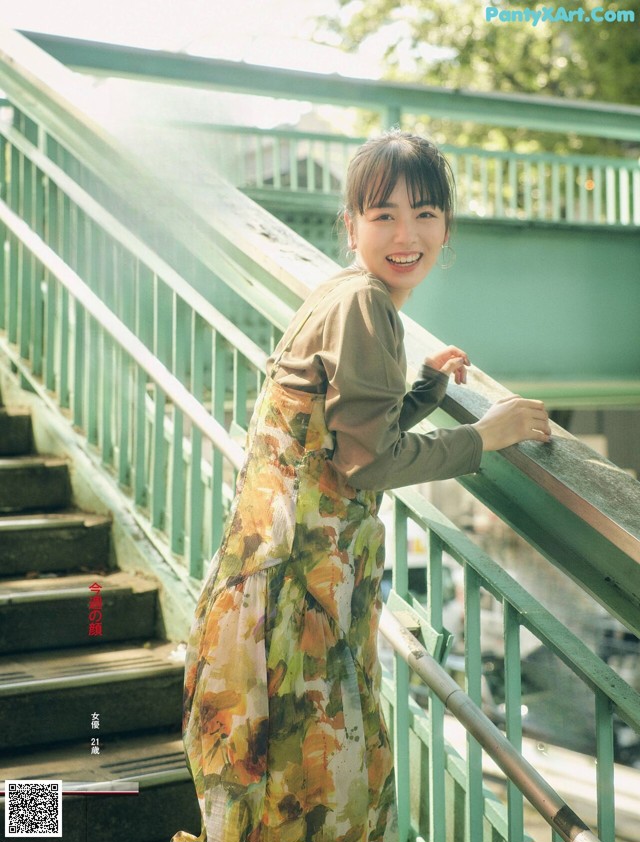 A woman in a long dress standing on a set of stairs.