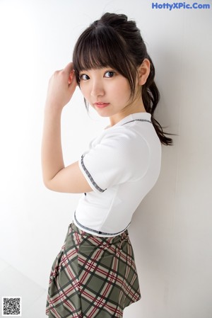 A young woman leaning against a white wall.