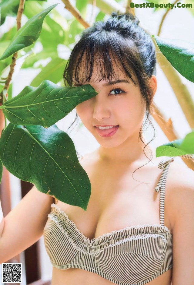 A woman in a bikini posing in front of a tree.