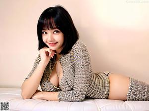 A woman in a silver top and shorts posing on a couch.