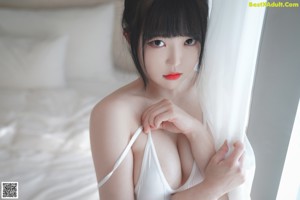 A naked asian woman standing in a bathroom next to a shower.