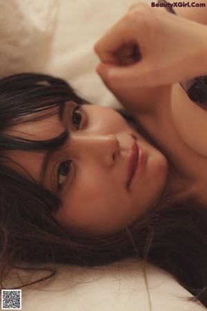 A woman in a black lingerie posing on a bed.