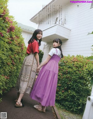 A couple of young women standing next to each other near a fence.