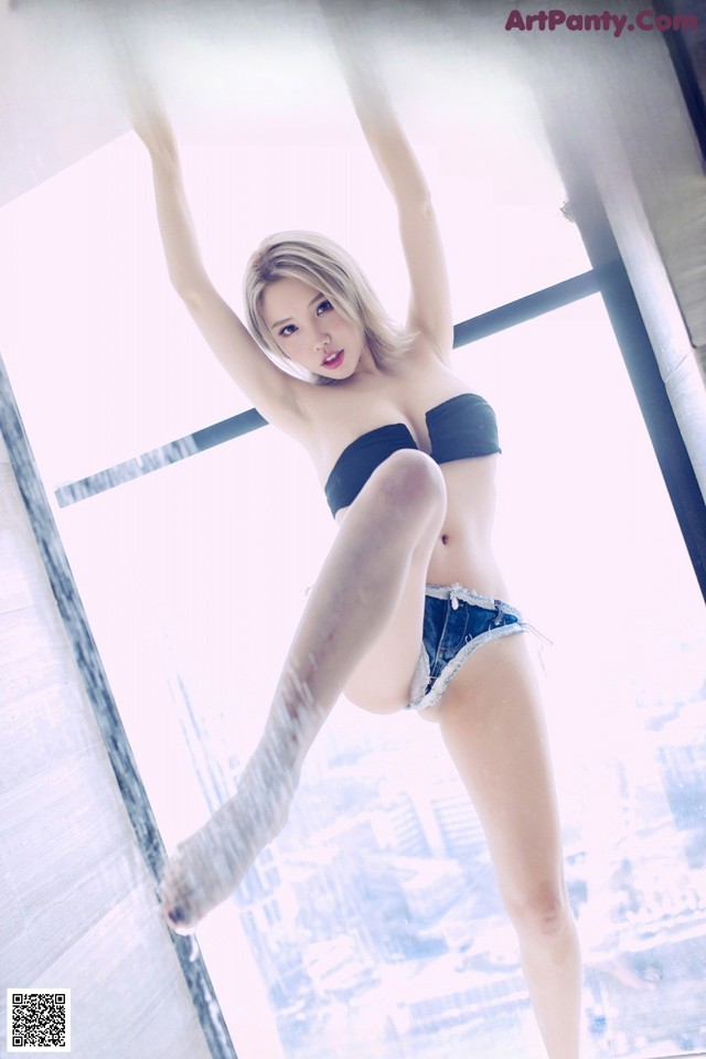 A woman in a black bra top and blue shorts posing for a magazine cover.