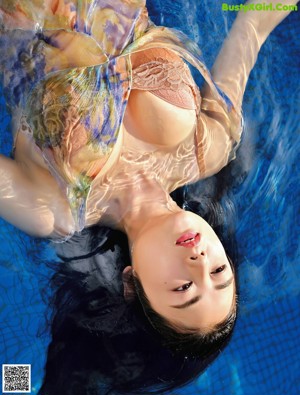 A woman in a bikini sitting on the edge of a pool.