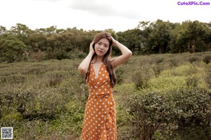 A woman in a black dress standing in the woods.